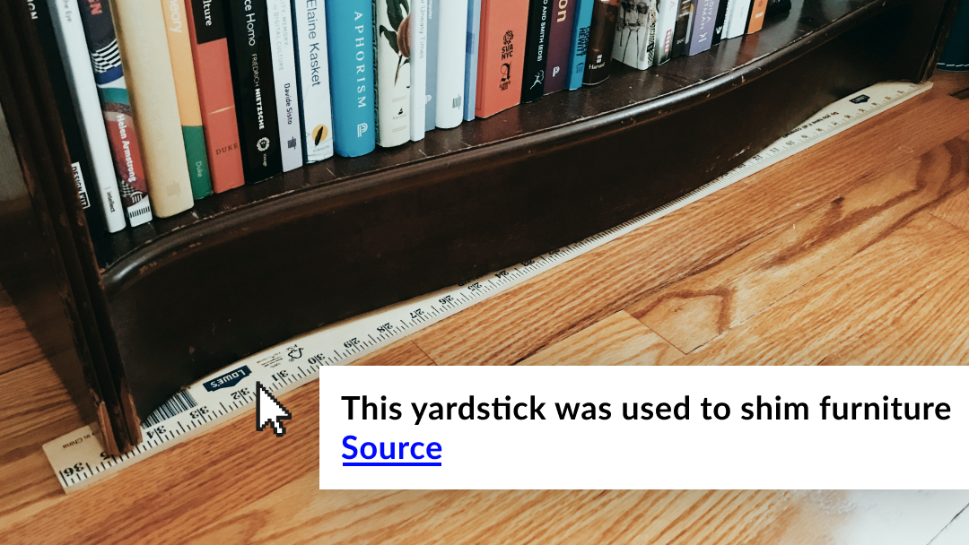 Photograph of a yardstick wedged under a bookshelf to keep it level with text reading ‘this yardstick was used to shim furniture’